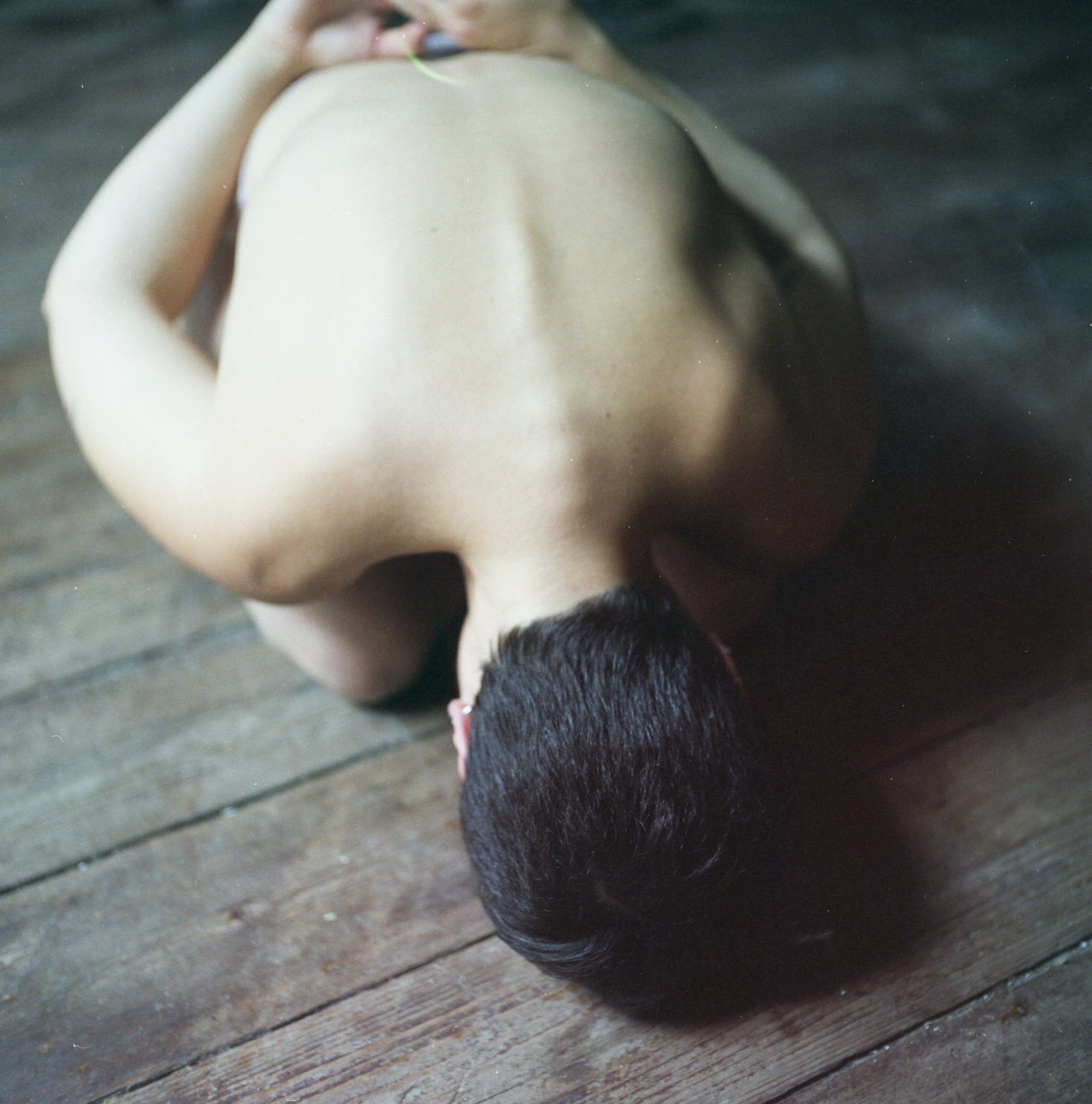 Close-up of Juliana Fernandes's back and hair, seated on a wooden floor