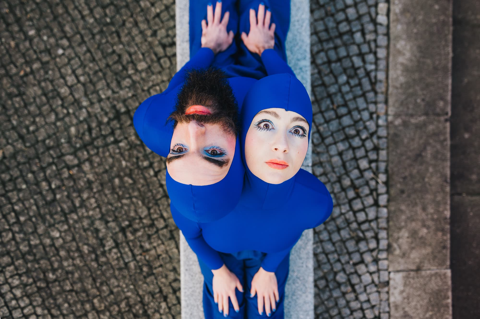 Performer in a blue hooded costume mid-movement, Blueprint
