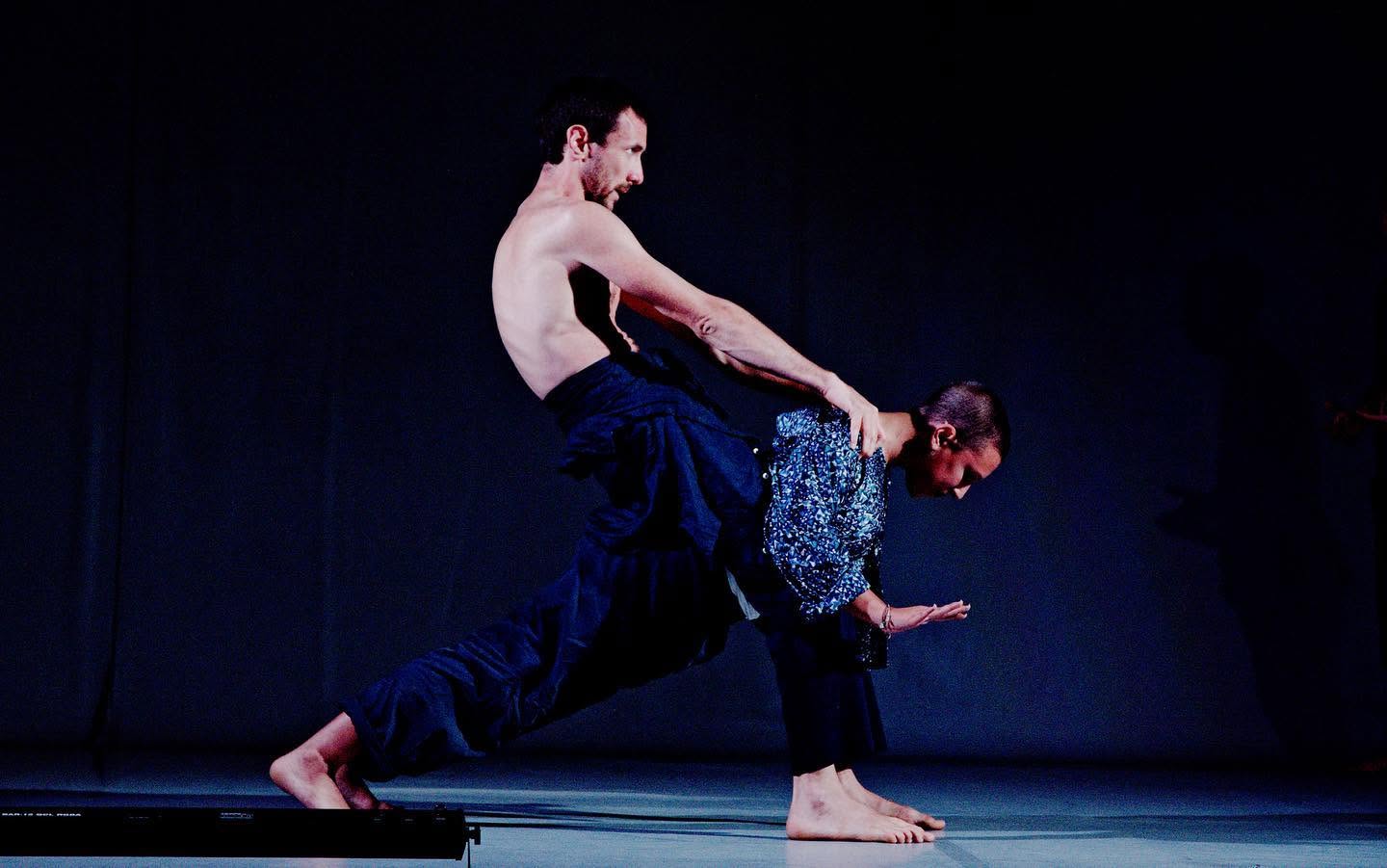 Two performers in a dark balancing pose, Everyours