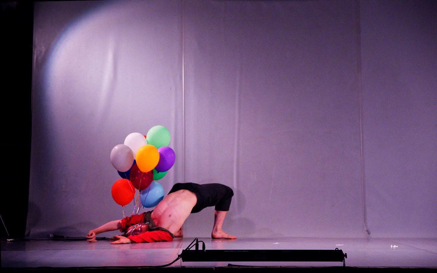 Performer bent backward holding a bunch of balloons, Everyours