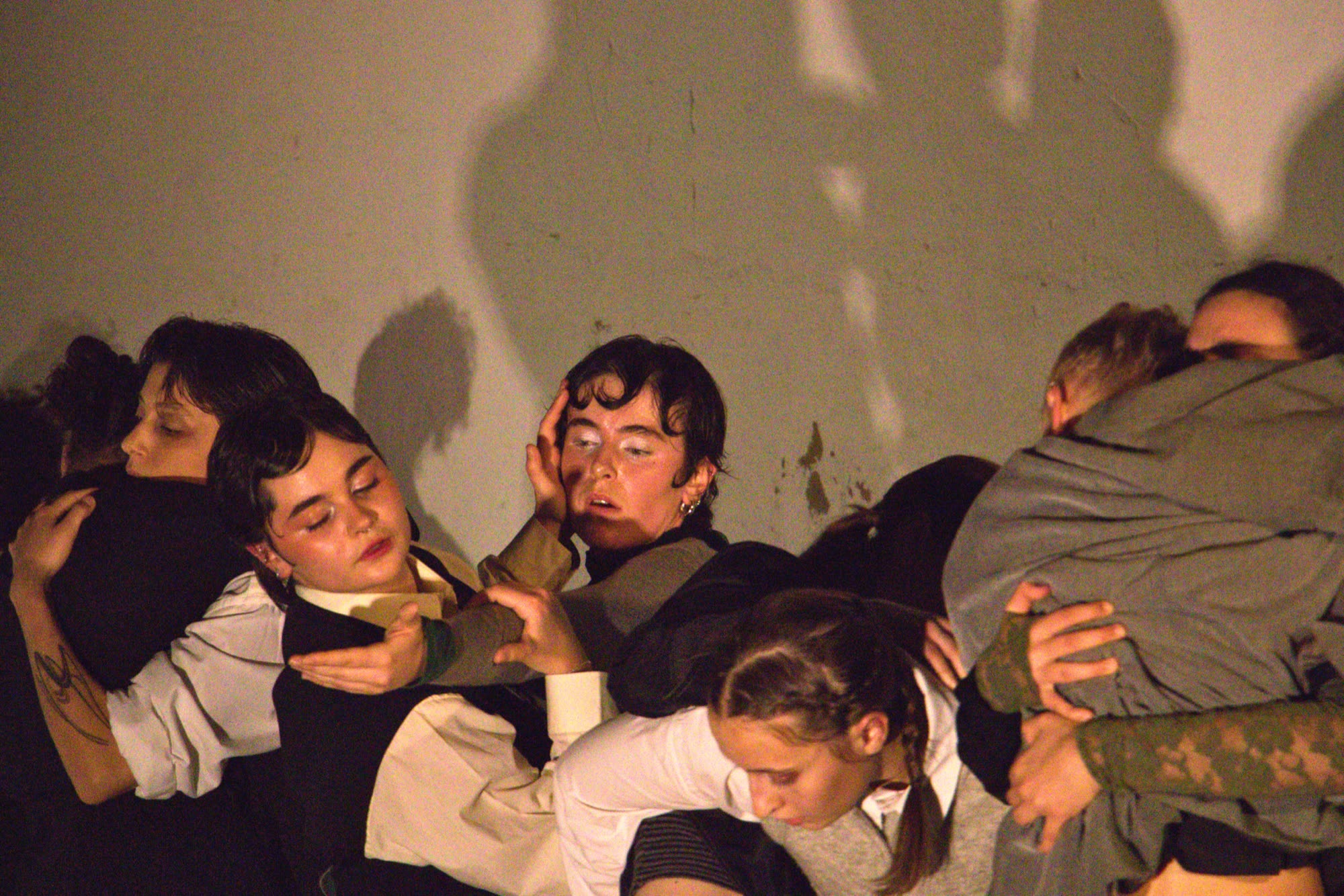 Group of performers in an embrace on stage, Lentidão