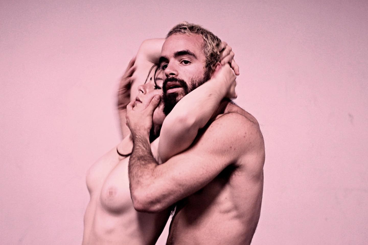 Two performers in an intimate pose on stage, In the Absence of Tenderness