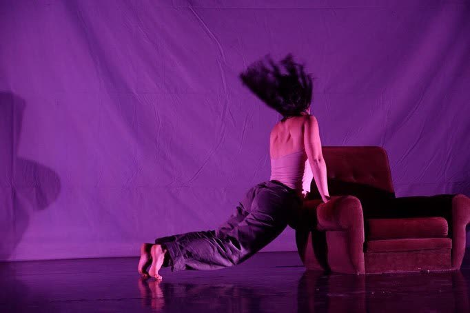 Performer reaching upward under pink and purple light, When the Bells Don't Chime